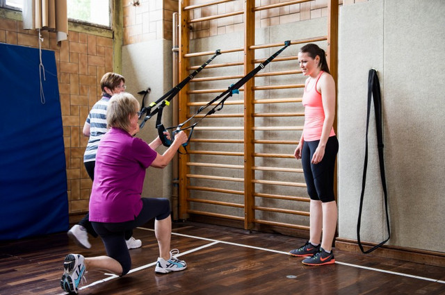 zwei Älter Menschen werden in einer Sporthalle angeleitet